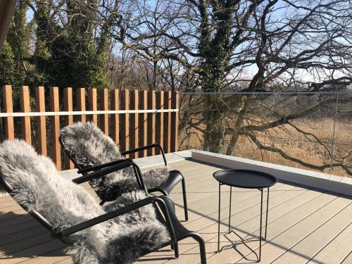 a chair sitting on a deck with a table at Swiss Lake Lodge in Noville