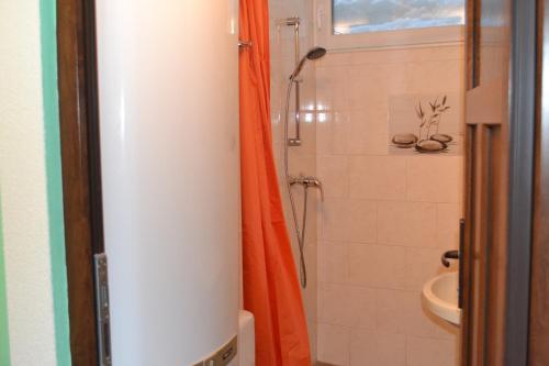 a bathroom with a shower with an orange shower curtain at Apartment Holiday Lungötz in Annaberg im Lammertal