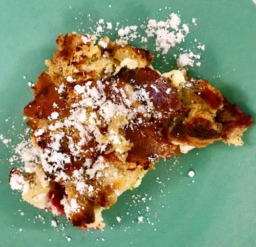 a piece of cake with powdered sugar on a green plate at Goldilocks Bed & Breakfast in Kodiak