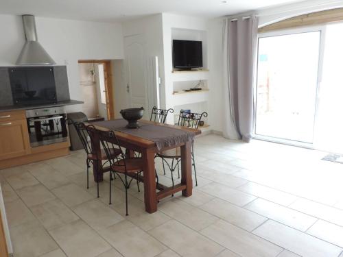 Il comprend une cuisine avec une table et des chaises en bois ainsi qu'une télévision. dans l'établissement La Maison d’Elise, à Beine
