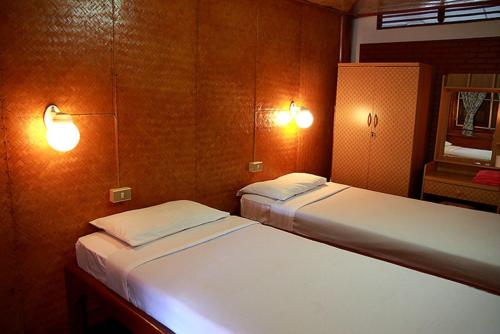 two beds in a room with two lights on the wall at Ben Guesthouse in Chiang Rai