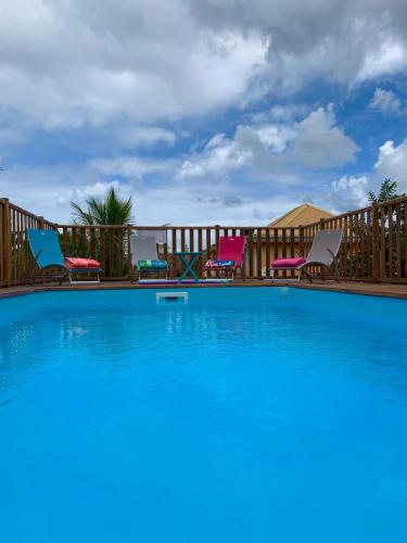 a large swimming pool with chairs and a fence at Villa Nord-Plage in Les Anses-dʼArlets