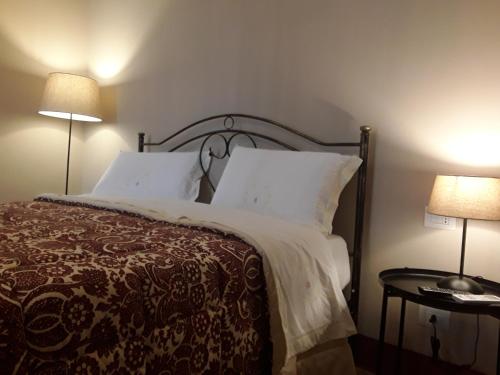 ein Schlafzimmer mit einem Bett mit weißen Kissen und zwei Lampen in der Unterkunft Dimora Don Francesco in Alberobello