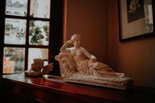 a statue of a woman sitting on a table next to a window at Hôtel Crystal Reims Centre in Reims