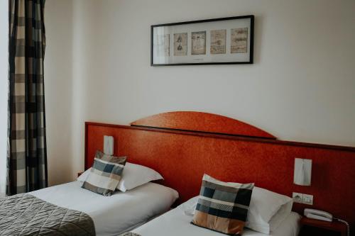 a hotel room with two beds and a picture on the wall at Hôtel Crystal Reims Centre in Reims