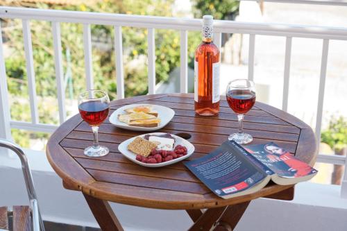 a wooden table with two glasses of wine and food at Syriti Studios in Skala Kefalonias