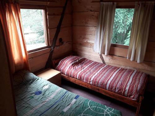 a bedroom with two beds in a log cabin at La Casa del Viajero Hostel in El Bolsón