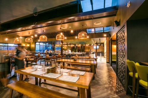 a restaurant with wooden tables and yellow chairs at Nightcap at Caringbah Hotel in Caringbah