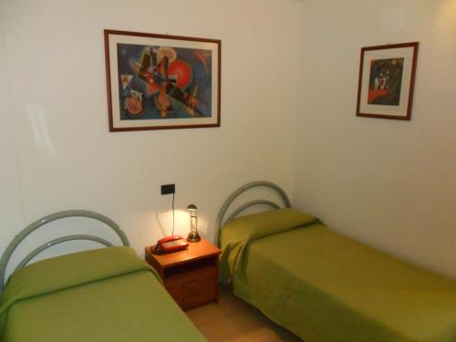 a room with two green beds and a telephone at Ospitalità San Tommaso d'Aquino in Bologna