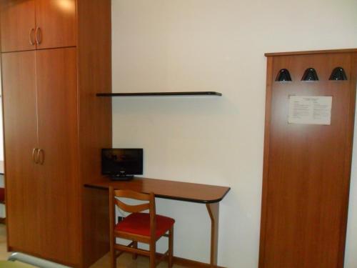 a room with a desk with a chair and a cabinet at Ospitalità San Tommaso d'Aquino in Bologna