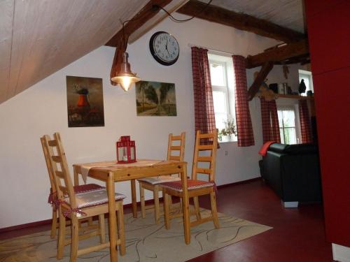 une salle à manger avec une table, des chaises et une horloge murale dans l'établissement Mühlenteich in der Oldenstädter Wassermühle, à Uelzen