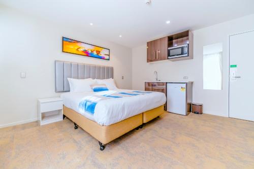 a bedroom with a large bed and a kitchen at Alpine Hotel in Christchurch