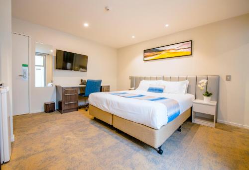a bedroom with a bed and a desk and a television at Alpine Hotel in Christchurch