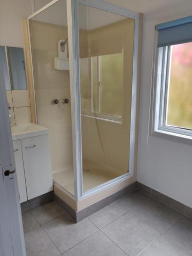 y baño con ducha de cristal y ventana. en Summers Rest Units, en Port Campbell