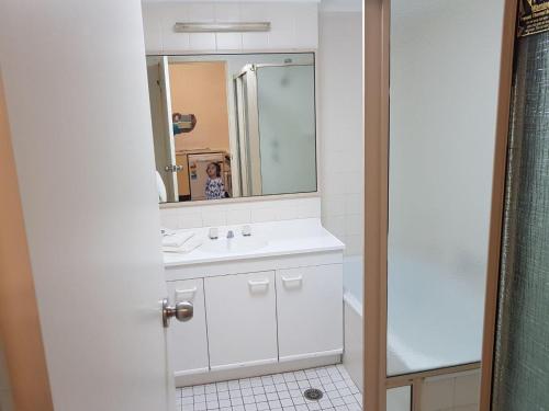 uma casa de banho com um lavatório branco e um espelho. em Beautiful inner city fully renovated ground floor apartment with attached lock-up garage em Camberra