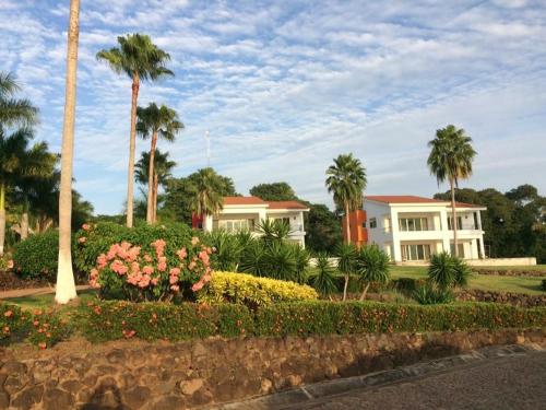 una gran casa blanca con palmeras y flores en Playa Limoncito Hills Fraccionamiento Vacacional Villas de 2 & 3 Recamaras con Alberca Privada o Alberca Compartida, en Limoncito Hill