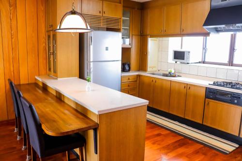 a kitchen with wooden cabinets and a white refrigerator at Condominium Hotel Mihama Upi in Chatan
