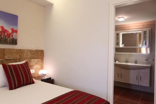 una camera da letto con un letto e un bagno con un lavandino di Monoberge Hotel a Jbeil