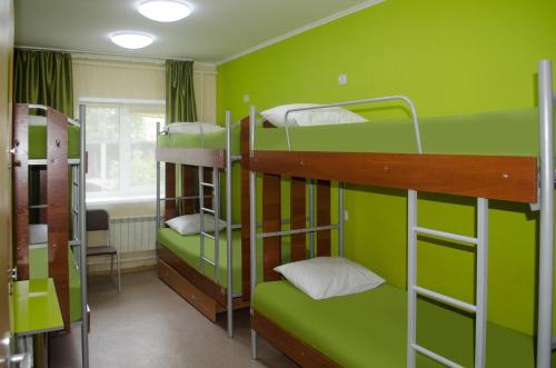 a room with three bunk beds with green walls at Millenium in Omsk