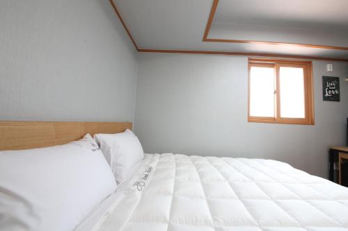 a white bed in a bedroom with a window at Gyeongju Bee House in Gyeongju