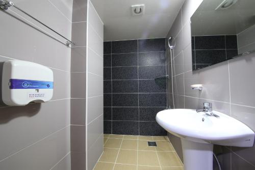 a white bathroom with a sink and a shower at Gyeongju Bee House in Gyeongju