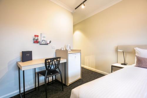a hotel room with a bed, desk, and chair at Nightcap at Hendon Hotel in Adelaide
