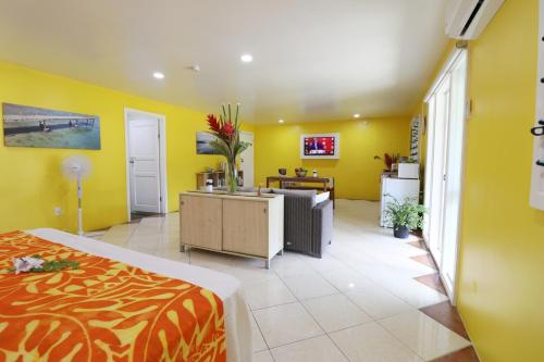 Habitación amarilla con cama y escritorio. en ShineAwayHomes - Mountain View AIR CONDITIONED, en Rarotonga