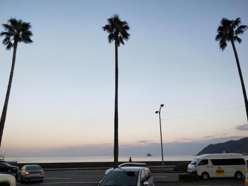 a parking lot with palm trees and the ocean at Izu Hokkawa Seaside Guesthouse 伊豆北川の家 in Higashiizu