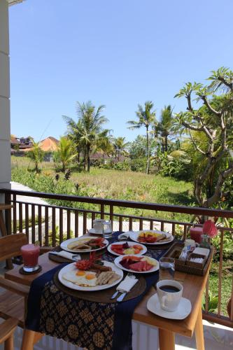 une table avec des assiettes de nourriture sur un balcon dans l'établissement Suarsena Villa Ubud, à Ubud