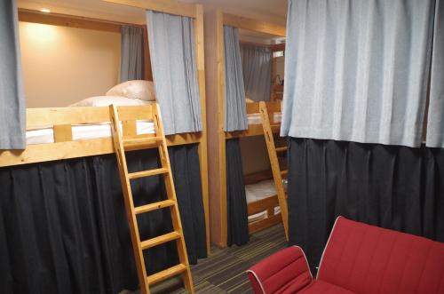 Schlafsaal mit 2 Etagenbetten und einem Stuhl in der Unterkunft Guesthouse POPTONE in Hiroshima