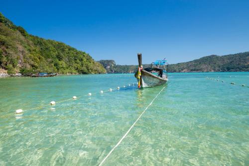 a boat is docked in the water on a beach at Phi Phi CoCo Beach Resort in Phi Phi Don