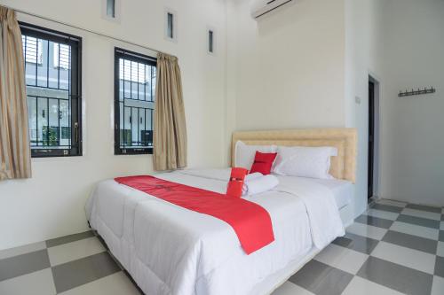 a white bed with a red blanket on it in a room at RedDoorz near Sultan Thaha Airport Jambi in Jambi