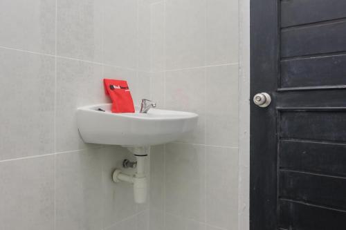 a white sink in a bathroom with a red towel at RedDoorz near Sultan Thaha Airport Jambi in Jambi