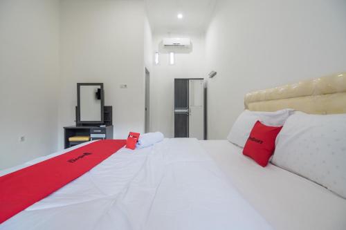 a bedroom with a white bed with red pillows at RedDoorz near Sultan Thaha Airport Jambi in Jambi