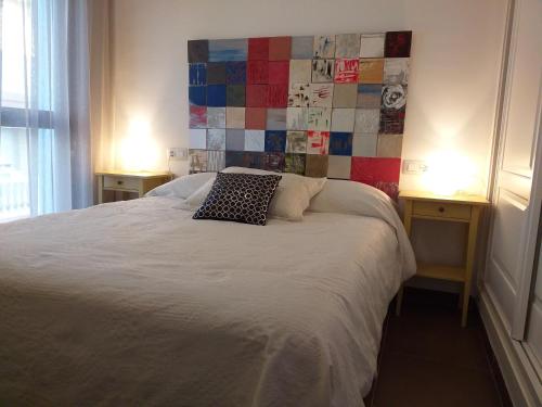 a bedroom with a white bed with two tables and a wall with tiles at Camarote in El Morche