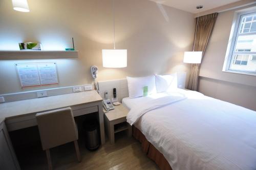 a hotel room with a bed and a desk at Kindness Hotel - Houyi Jiuru in Kaohsiung