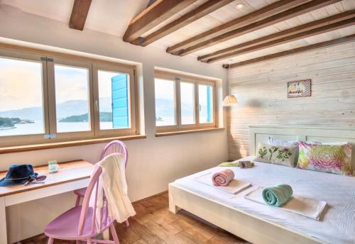 a bedroom with a bed and a desk and windows at ECO Aparthotel The Dreamers's Club in Lumbarda