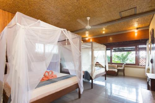 Schlafzimmer mit 4 Betten und Moskitonetzen in der Unterkunft Rumah Roda in Ubud