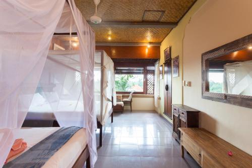 a bedroom with a bed with a mosquito net at Rumah Roda in Ubud