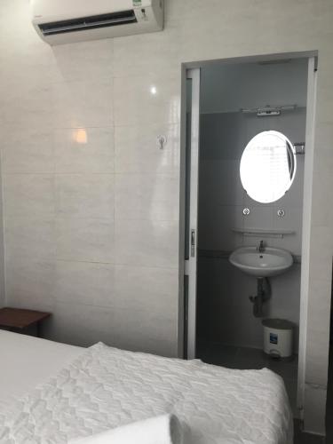 a bedroom with a white bed and a sink at Vy Khanh Guesthouse in Ho Chi Minh City