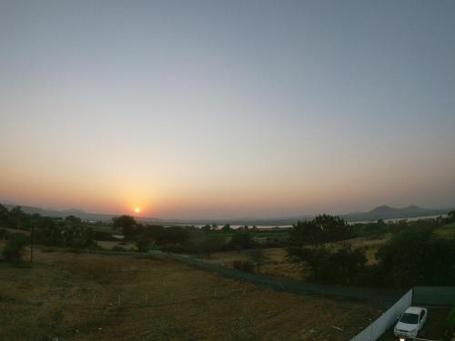 a sunset in the middle of a field with a van at Tripvana Patio Home in Nashik