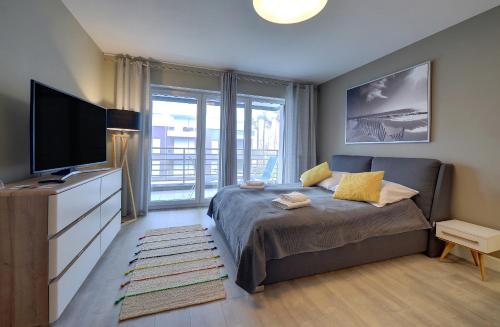 ein Schlafzimmer mit einem Bett und einem Flachbildfernseher in der Unterkunft Komfortowe Apartamenty Sun Seasons 24 w Pogorzelicy Blisko Morza by Noclegi Renters in Pogorzelica