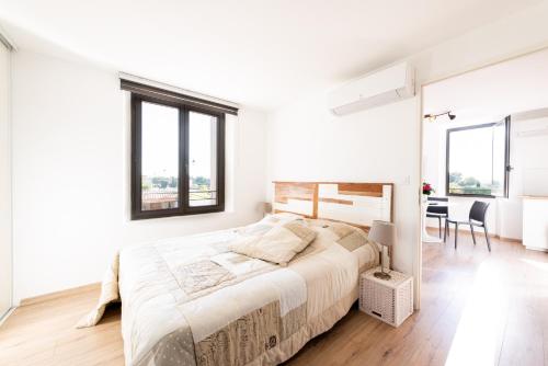 a white bedroom with a large bed and a desk at chez nico in Bédoin