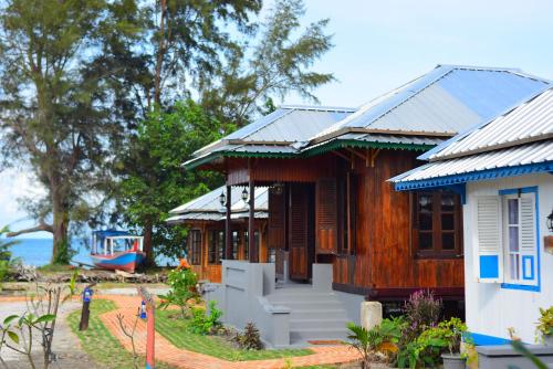 a house on the beach with a boat in the background at Rock and Wreck Dive Resort in Tanjungbinga
