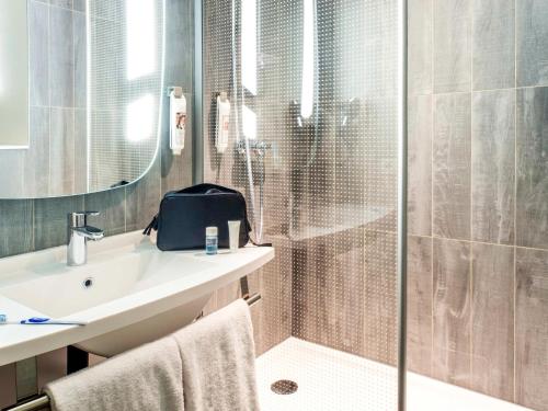 a bathroom with a shower and a sink and a mirror at ibis Gonesse in Gonesse