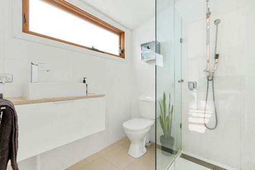 a bathroom with a toilet and a glass shower at Geelong West Miner's Cottage in Geelong