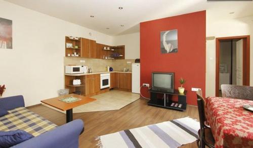 a living room with a red wall and a kitchen at Palatinus Apartment in Budapest