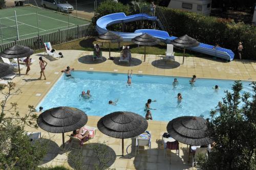 a swimming pool with people in the water and umbrellas at Camping Torraccia in Cargèse