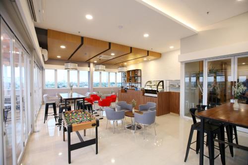 uma sala de jantar com mesas, cadeiras e janelas em Cordela Hotel Cirebon em Cirebon