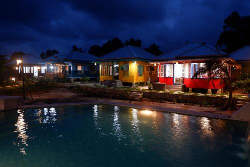 a group of houses at night with a swimming pool at Rock and Wreck Dive Resort in Tanjungbinga